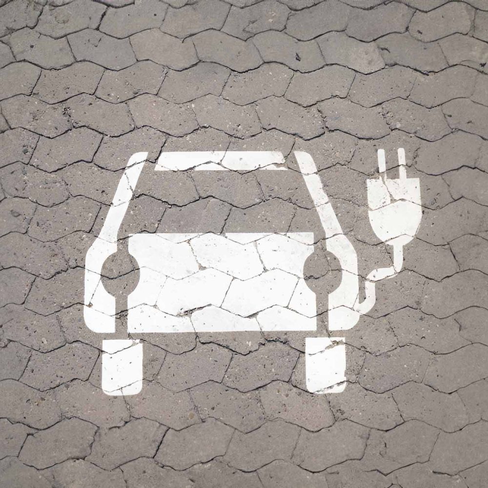 Symbol für das aufladen von E-Autos in weiß auf den Boden gemalt.